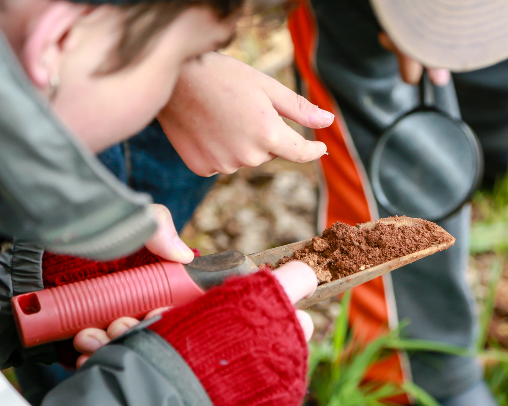 student with trowel full of soil